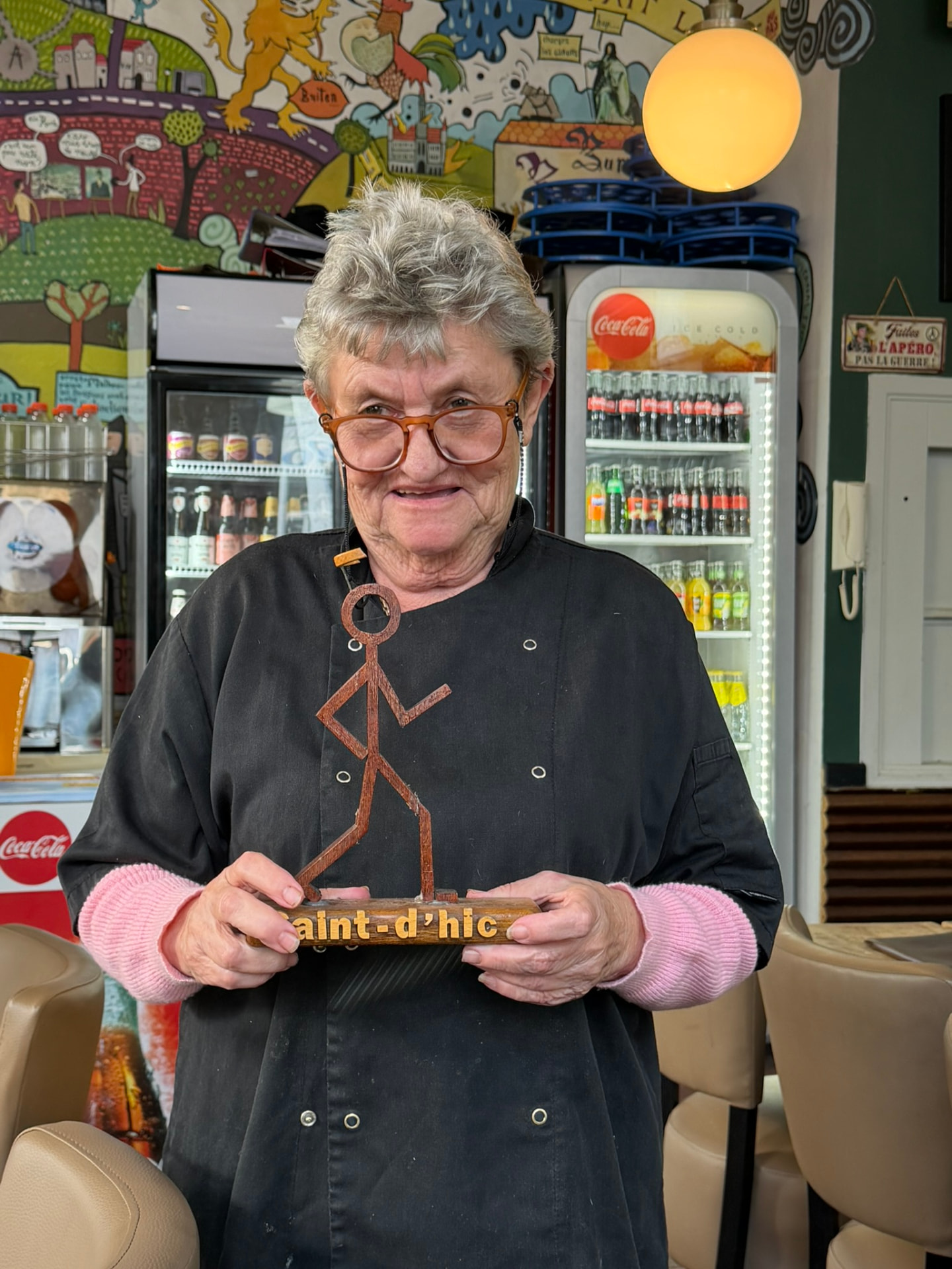 Marianne tenant l'enseigne en bois du Saint d'Hic